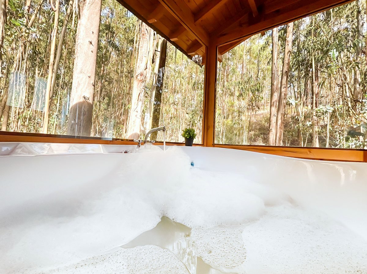 Jacuzzi lleno de espuma en el Domo Col Loze con el bosque de eucaliptos al fondo