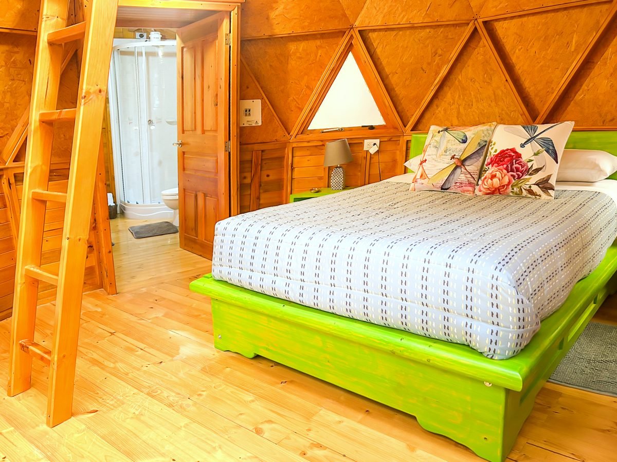Cama doble del Domo Gamoniteiru bajo la estructura de madera