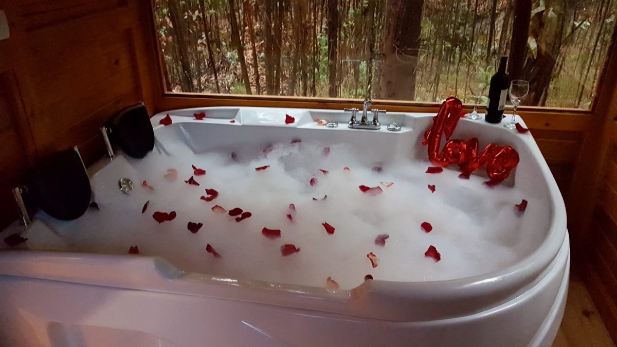 Jacuzzi decorado con pétalos de rosa para un plan romántico en el glamping