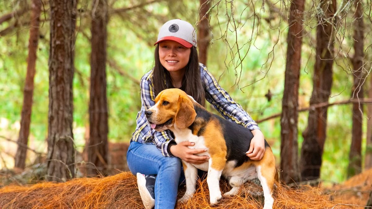 Huésped abrazando a su perro beagle en el bosque del glamping, en Pesca, Boyacá